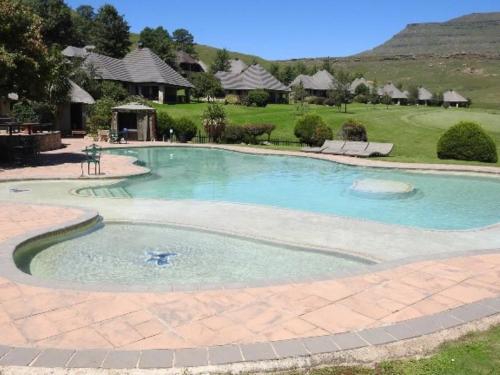 a large swimming pool with blue water in a yard at Fairways Holiday Accommodation in Drakensberg Garden