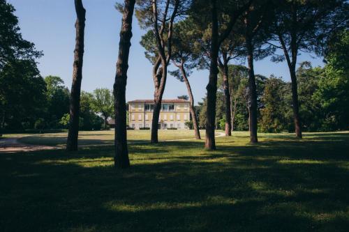 a building in the middle of a park with trees at Villa Abbondanzi Resort in Faenza