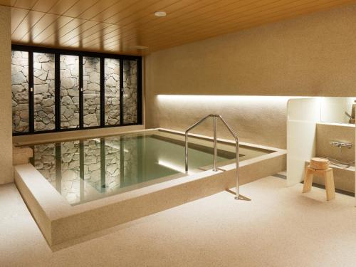 hotel androoms Kyoto Shichijo في كيوتو: حوض استحمام في غرفة مع نافذة