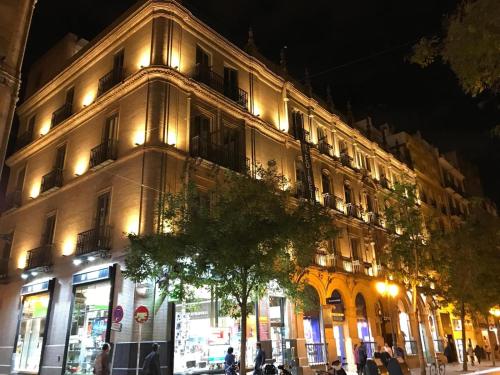 a large building on a city street at night at Aquitania Home Suites in Seville