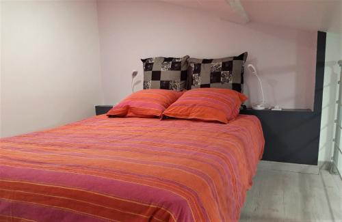 - une chambre avec un lit et deux oreillers orange dans l'établissement Gîte de charme au coeur du vignoble de St Emilion, à Génissac