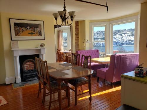 uma sala de jantar com uma mesa e cadeiras e uma lareira em The Roses Heritage Inn em St. John's