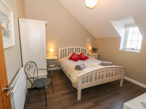a bedroom with a white bed with red pillows at Tan Bryn 1 in Aberdaron