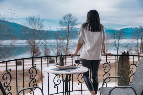 una mujer parada en un balcón con una copa de vino en Akti Hotel Ioannina, en Ioannina