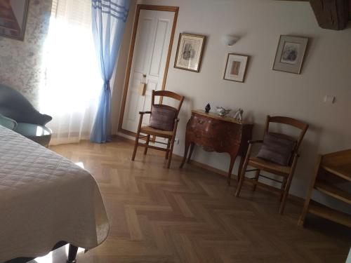 a bedroom with a bed and two chairs and a desk at Logis Saint Martin in Magny-lès-Villers