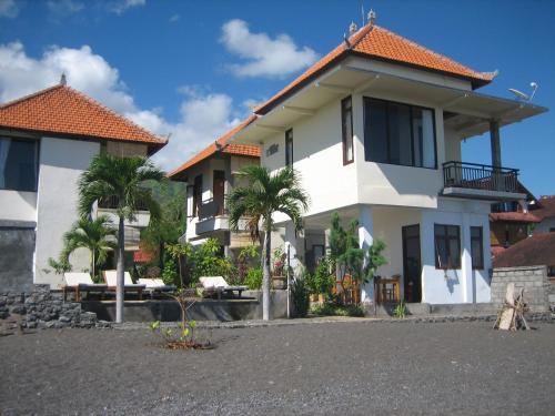 a white house with palm trees in front of it at Lucky Paradise Bungalows on The Beach in Amed