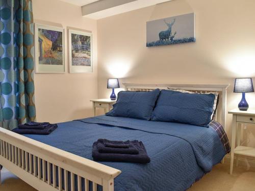 a bedroom with a blue bed with two tables and two lamps at Lovely 2 bedroom apt in Ballater on the River Dee in Ballater