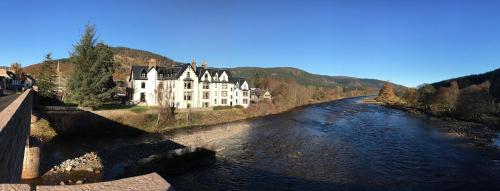 a large house on the side of a river at Lovely 2 bedroom apt in Ballater on the River Dee in Ballater