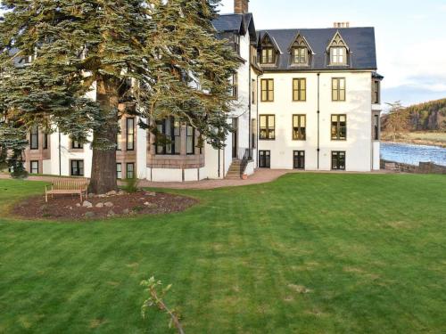 a large white house with a tree in the yard at Lovely 2 bedroom apt in Ballater on the River Dee in Ballater