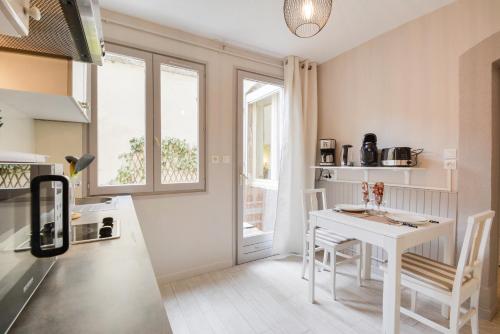 - une cuisine avec une table et une table et des chaises blanches dans l'établissement Le Bailly, à Nancy