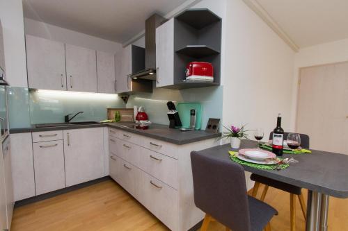 a kitchen with white cabinets and a table with a bottle of wine at Ferienparadies Bodensee Fewo1 in Owingen