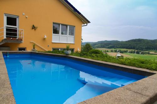 a blue swimming pool in front of a house at Ferienparadies Bodensee Fewo1 in Owingen