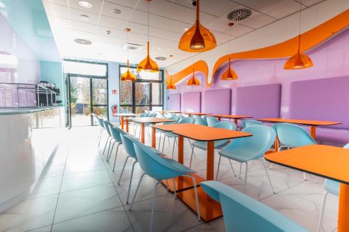 a colorful restaurant with tables and chairs at Prize by Radisson, Rostock City in Rostock