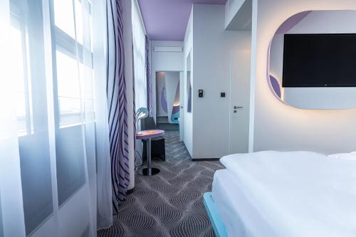 a hotel room with a bed and a tv at Prize by Radisson, Rostock City in Rostock