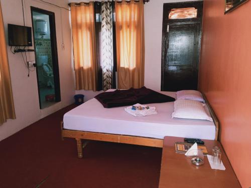 Dormitorio pequeño con cama y mesa en Debbhumi Regency, en Sāngla