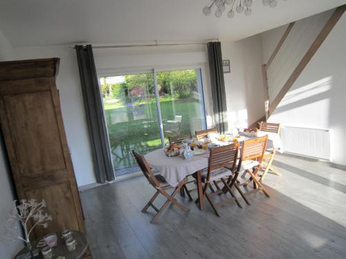 une salle à manger avec une table et des chaises et une grande fenêtre dans l'établissement Les Chambres de Pascaline, à Arrest