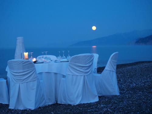 a table and chairs with the moon in the background at Thalatta Seaside Hotel in Ayia anna