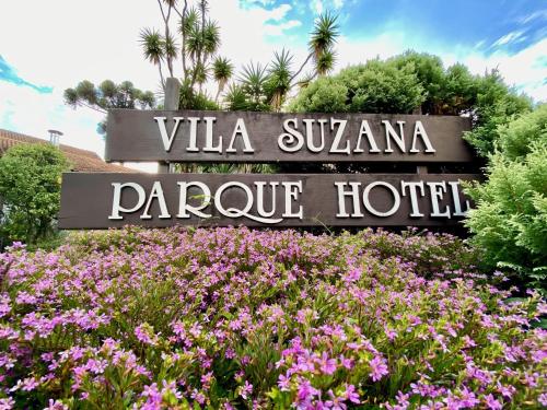a sign in a field of flowers in front of a hotel at Vila Suzana Parque Hotel in Canela