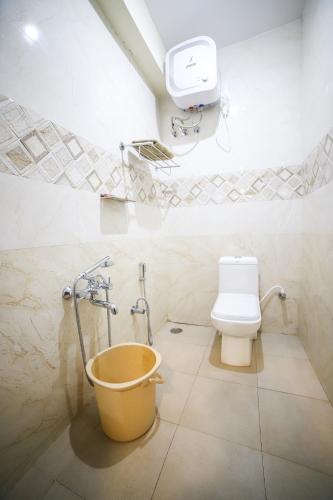 a bathroom with a toilet and a bucket at Aira Residency Kothagiri by Lexstays in Kotagiri