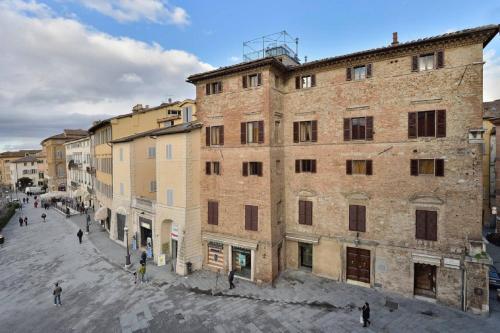 - un grand bâtiment en briques avec des personnes marchant dans une rue dans l'établissement Residenze d'Epoca Palazzo Coli Bizzarrini, à Sienne