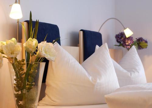 a table with white pillows and flowers in a vase at Rebhan's Klassik in Stockheim Oberfranken