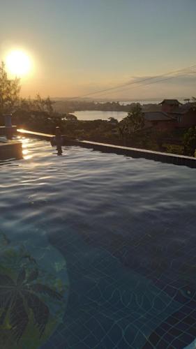 una grande piscina con il tramonto sullo sfondo di Hotel Pousada Casacolina a Búzios