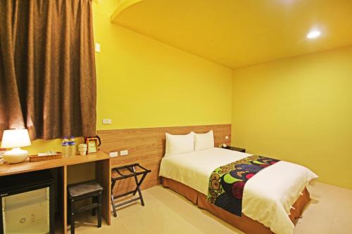 a hotel room with a bed and a desk and a window at Fun Trip - Little Castle & Oscar B&B in Taitung City