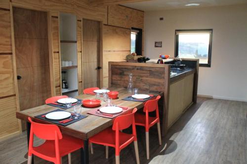 eine Küche mit einem Holztisch und roten Stühlen in der Unterkunft Cabañas Vista Volcanes del Sur in Llanquihue