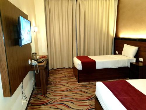 a hotel room with two beds and a flat screen tv at Hayah Golden Hotel in Al Madinah
