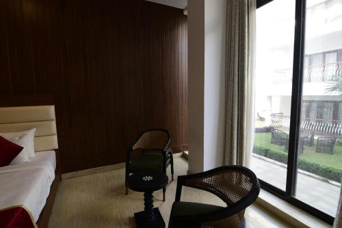 a hotel room with two chairs and a bed and a window at Park Regis Goa in Arpora