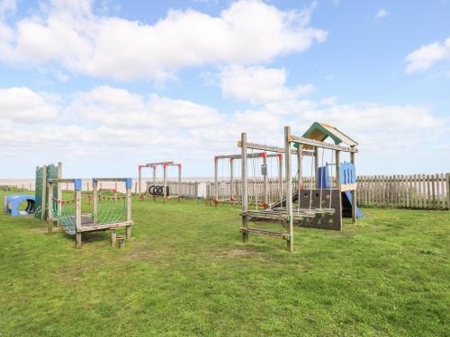 a row of empty playground equipment in a field at Villa 109 in Lowestoft