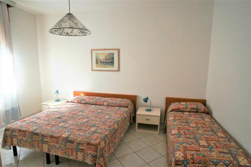 a bedroom with two beds and a table and a lamp at Diplomatic Apartment in Lido di Jesolo