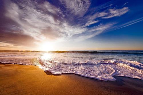 a sunset on a beach with the ocean at Regenbogen Properties - Salgados Vila das Lagoas in Albufeira