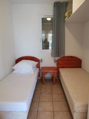 une petite chambre avec deux lits et une table dans l'établissement Résidence le cordouan, à Soulac-sur-Mer