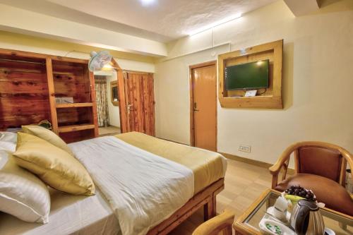 a bedroom with a bed and a tv on the wall at Hotel Ibex in Manāli