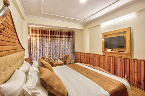 a hotel room with a bed and a television at Hotel Ibex in Manāli