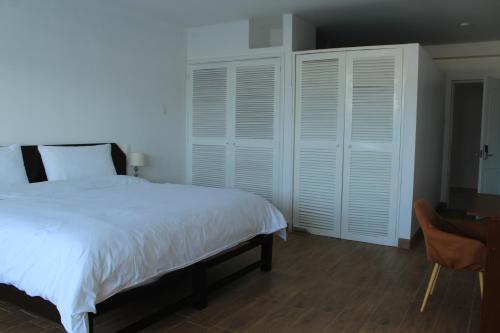 a bedroom with a large white bed and a desk at La Casa de Algodon in Huacho