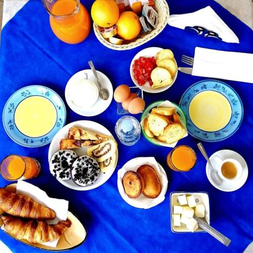 a blue table with plates of breakfast foods and orange juice at Bed&Belvedere in Otranto