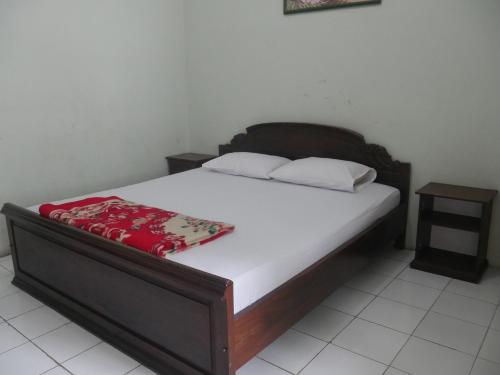 a bed with a wooden frame and white sheets at Hotel Garuda Syariah near Alun Alun Banjarnegara in Wonosobo