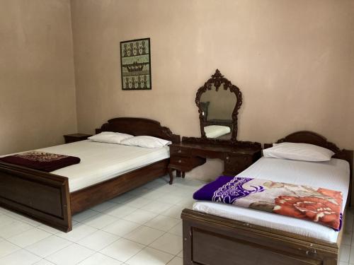 a bedroom with two beds with a mirror and a dresser at Hotel Garuda Syariah near Alun Alun Banjarnegara in Wonosobo