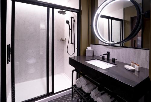 a bathroom with a sink and a shower with a mirror at Hotel Indigo - Columbus at Riverfront Place by IHG in Columbus