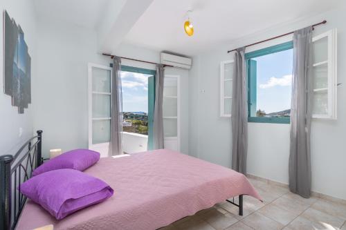a bedroom with a bed with purple pillows and windows at Zanart maisonette II in Tripití