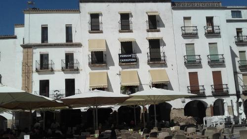 un edificio con mesas y sombrillas delante en Pension Carretero, en Cáceres
