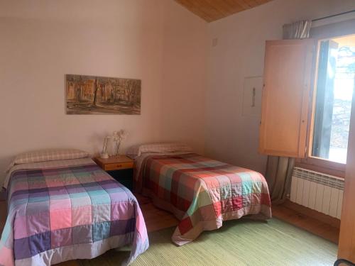a bedroom with two beds and a window at casa rural de un artista en plena naturaleza piscina y parque de esculturas en villarcayo in Villarcayo