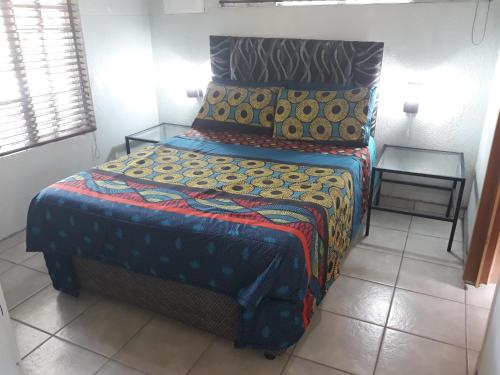 um quarto com uma cama com um cobertor colorido em African Sky em Marloth Park