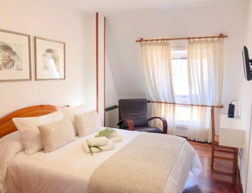 a bedroom with a large white bed and a chair at Pensión As Burgas in Caldas de Reis