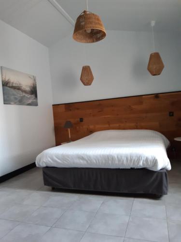 a bedroom with a bed with a wooden headboard at L'Ile sous le Vent in Sainte-Marie-de-Ré