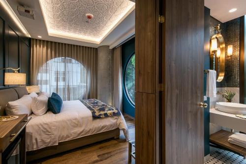 a bedroom with a bed and a bathroom with a sink at Hotel Marquee Medellín in Medellín