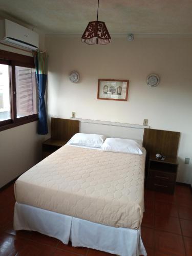 a bedroom with a white bed in a room at Pousada Japeju in Capão da Canoa