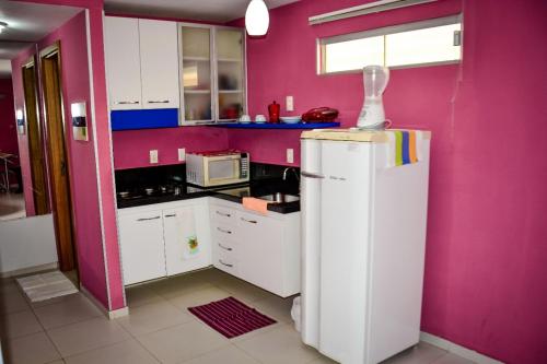 cocina con paredes rosas y nevera blanca en Residence Victoria Brasil, en Natal